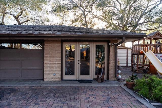 property entrance featuring a garage, french doors, and brick siding