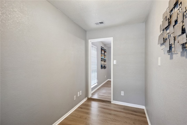 hallway featuring hardwood / wood-style floors and a textured ceiling