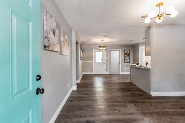 foyer with dark wood-type flooring, a chandelier, and a textured ceiling