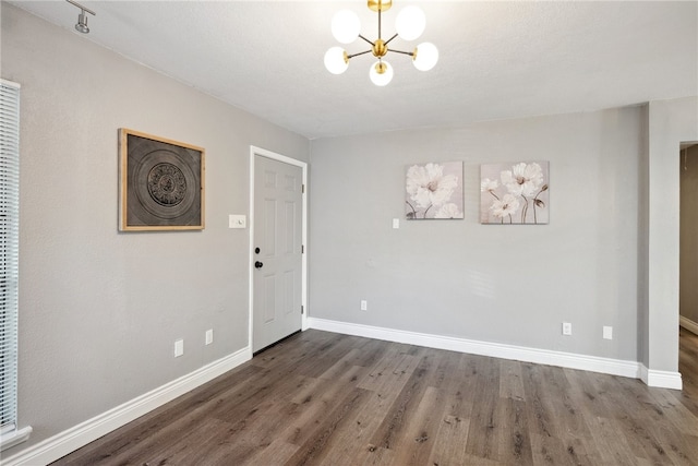 interior space featuring dark wood-type flooring, a textured ceiling, and an inviting chandelier