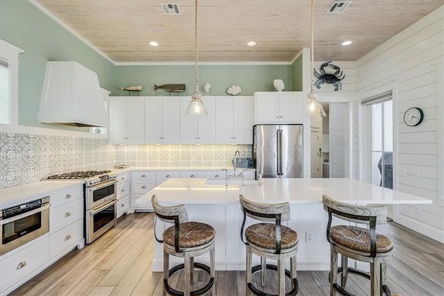 kitchen featuring stainless steel appliances, custom range hood, light wood-style floors, and visible vents