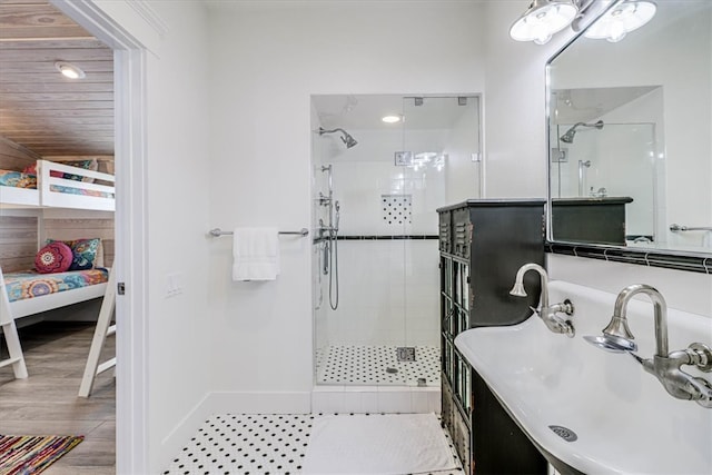 ensuite bathroom featuring a stall shower, ensuite bath, a sink, and wood finished floors