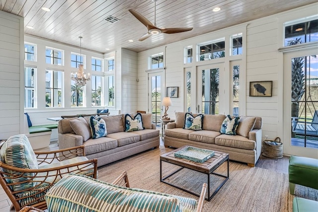 sunroom / solarium featuring ceiling fan with notable chandelier, wooden ceiling, visible vents, and a healthy amount of sunlight