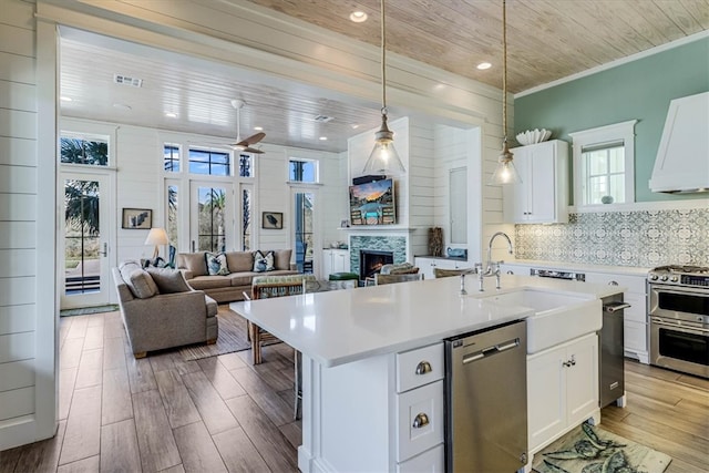 kitchen with appliances with stainless steel finishes, a warm lit fireplace, wood ceiling, and light countertops