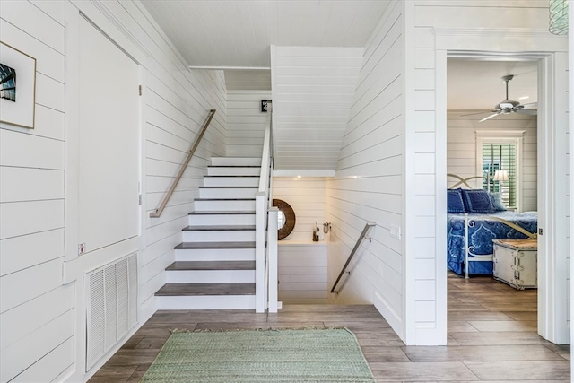 stairway featuring wood finished floors, visible vents, and a ceiling fan