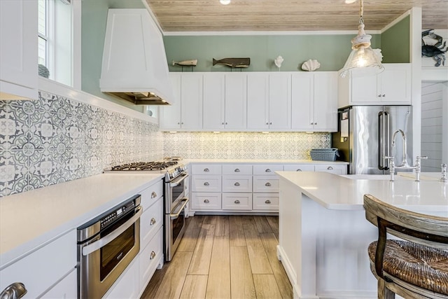 kitchen featuring stainless steel appliances, custom exhaust hood, light countertops, and decorative backsplash