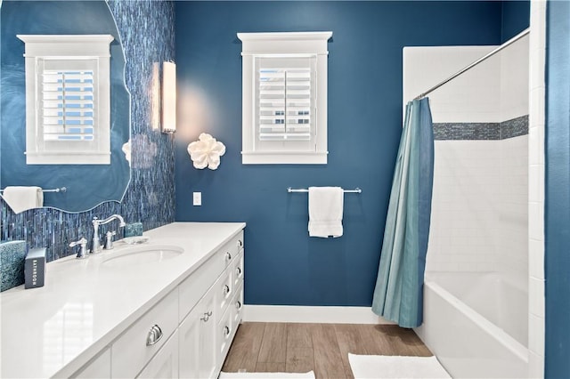 full bath with plenty of natural light, vanity, baseboards, and wood finished floors