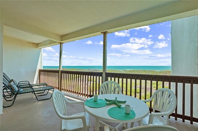 sunroom featuring a beach view and a water view