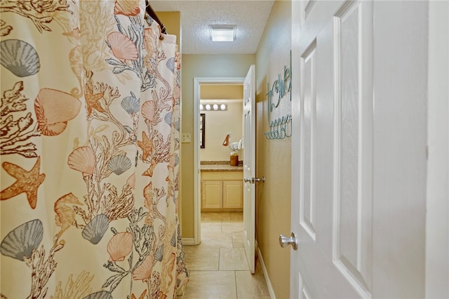 hall featuring a textured ceiling and light tile patterned floors