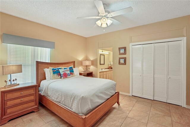 bedroom with light tile patterned flooring, ceiling fan, a textured ceiling, connected bathroom, and a closet