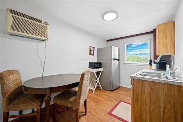 dining space featuring a wall mounted AC, light wood-type flooring, and sink