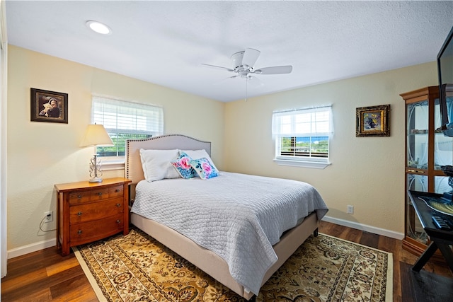 bedroom featuring dark hardwood / wood-style flooring, multiple windows, and ceiling fan