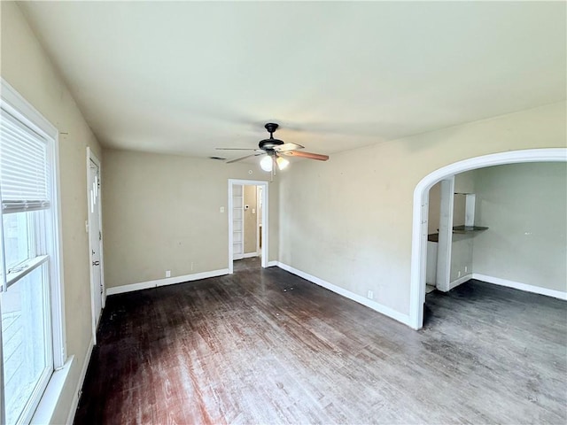 spare room featuring ceiling fan, arched walkways, baseboards, and wood finished floors