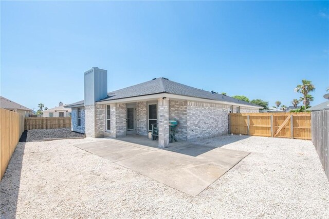 13948 Lighthouse Dr, Corpus Christi, TX 78418 - rear view of property with a patio area, a chimney, a fenced backyard, and brick siding
