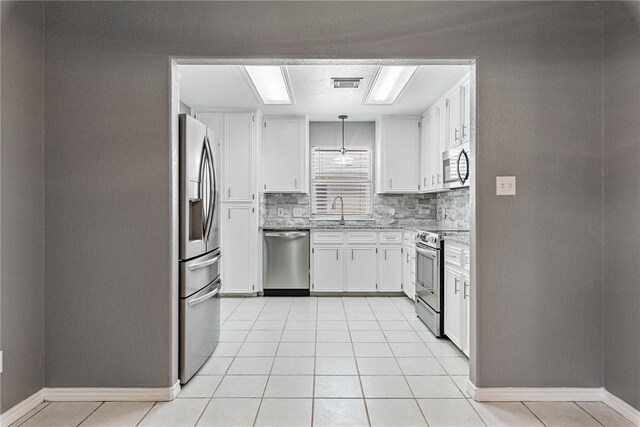 13948 Lighthouse Dr, Corpus Christi, TX 78418 - kitchen with appliances with stainless steel finishes, decorative backsplash, a sink, white cabinets, and baseboards