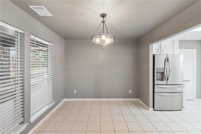 13948 Lighthouse Dr, Corpus Christi, TX 78418 - kitchen with stainless steel fridge with ice dispenser, light tile patterned flooring, white cabinetry, baseboards, and pendant lighting