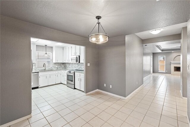13948 Lighthouse Dr, Corpus Christi, TX 78418 - kitchen with appliances with stainless steel finishes, plenty of natural light, a textured ceiling, white cabinetry, and light tile patterned floors