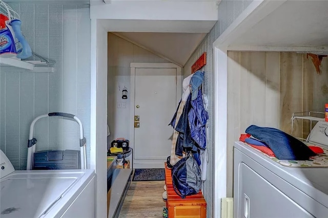 laundry area with hardwood / wood-style flooring, washer and clothes dryer, and wood walls