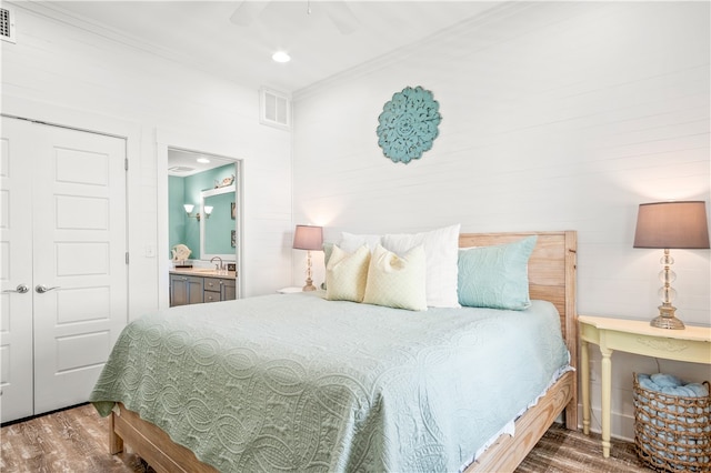 bedroom featuring sink, ensuite bathroom, dark hardwood / wood-style floors, ceiling fan, and a closet