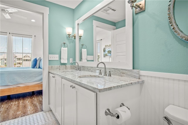 bathroom featuring toilet, vanity, hardwood / wood-style flooring, and ceiling fan