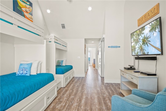 bedroom with high vaulted ceiling and light hardwood / wood-style floors