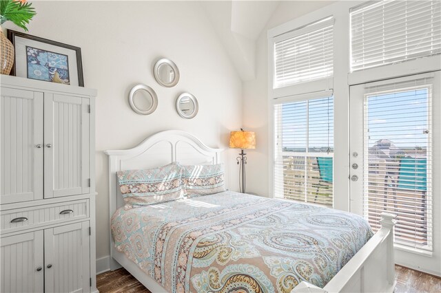 bedroom with access to exterior, hardwood / wood-style flooring, and vaulted ceiling