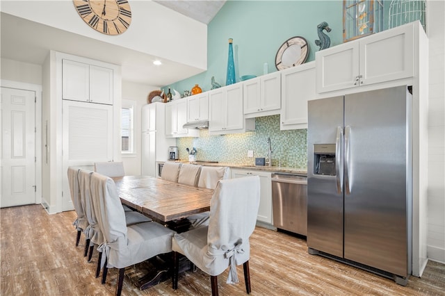 kitchen with stainless steel appliances, white cabinets, light hardwood / wood-style flooring, and decorative backsplash