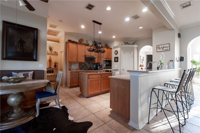 7602 Beau Terre, Corpus Christi, TX 78414 - kitchen with arched walkways, ornamental molding, a kitchen breakfast bar, black microwave, and a peninsula