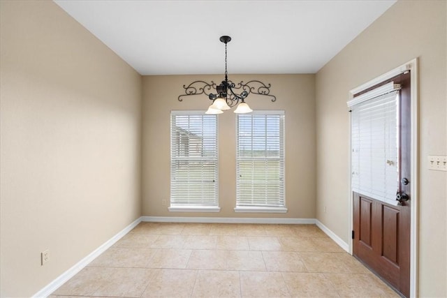 unfurnished dining area featuring light tile patterned flooring, baseboards, and a chandelier