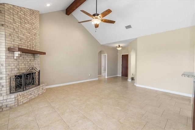 unfurnished living room featuring a brick fireplace, baseboards, ceiling fan, beam ceiling, and arched walkways