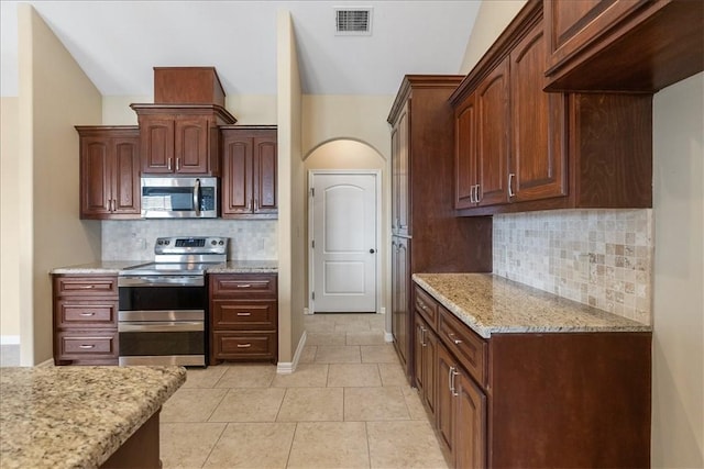kitchen featuring tasteful backsplash, light tile patterned floors, stainless steel appliances, visible vents, and light stone countertops