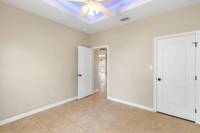 empty room with baseboards, ceiling fan, visible vents, and light tile patterned floors