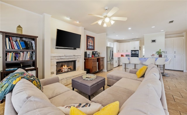 living room featuring crown molding, a fireplace, ceiling fan, and light tile patterned flooring