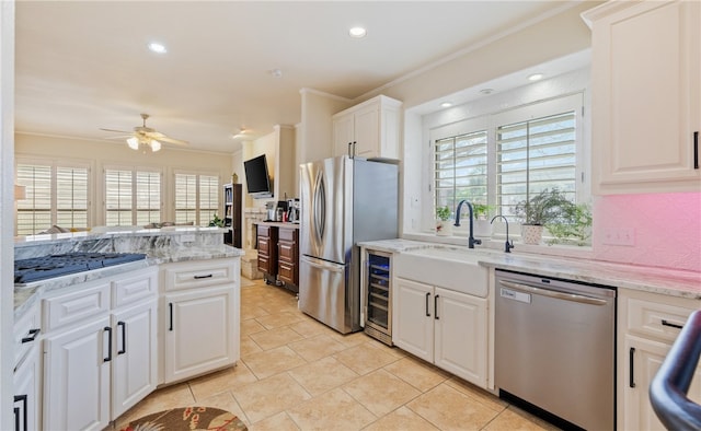 kitchen featuring appliances with stainless steel finishes, white cabinetry, sink, ornamental molding, and light stone countertops