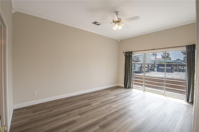 spare room with wood finished floors, baseboards, visible vents, a ceiling fan, and crown molding