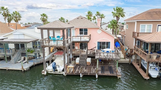 rear view of house featuring a water view, stairway, and stucco siding
