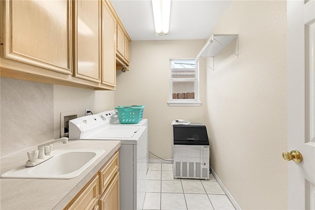 washroom featuring light tile patterned floors, washing machine and dryer, cabinet space, and a sink