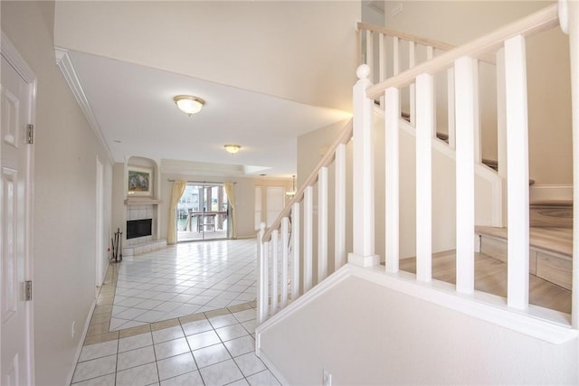 staircase with tile patterned floors, baseboards, and a fireplace with raised hearth