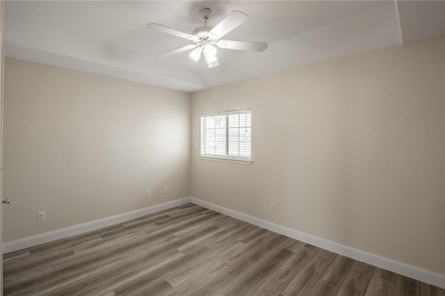 spare room with ceiling fan, light wood-style flooring, and baseboards