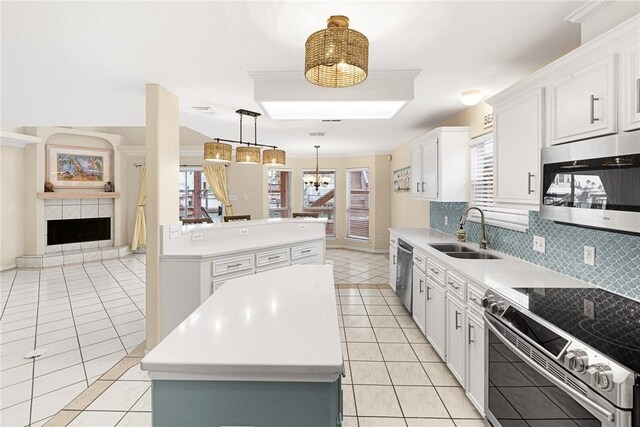 kitchen featuring a sink, light tile patterned floors, a center island, backsplash, and appliances with stainless steel finishes