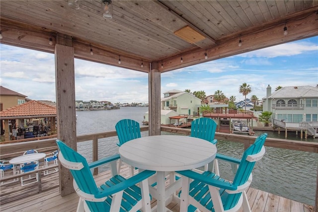 wooden deck featuring outdoor dining area, a residential view, and a water view