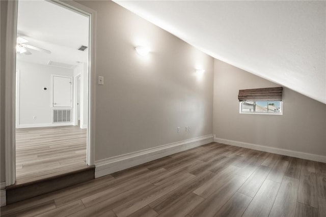 additional living space with lofted ceiling, wood finished floors, visible vents, and baseboards