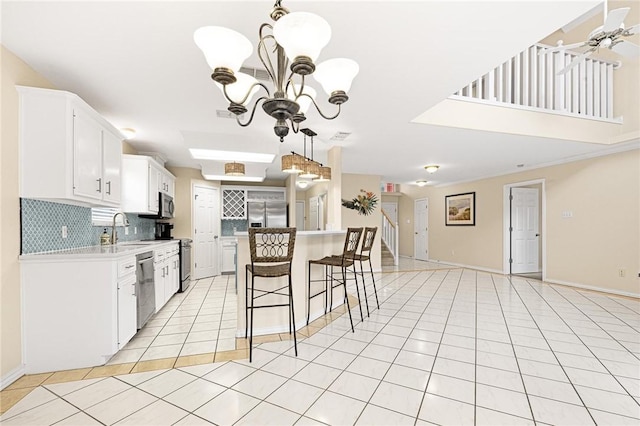 kitchen with appliances with stainless steel finishes, backsplash, a sink, open floor plan, and light tile patterned flooring