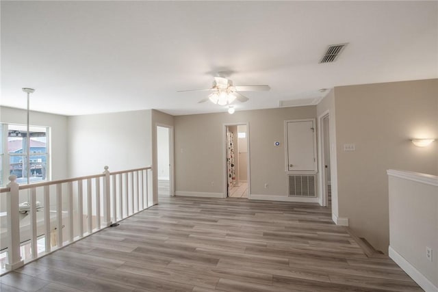 unfurnished room with baseboards, visible vents, wood finished floors, and a ceiling fan