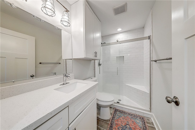 bathroom with toilet, vanity, and a shower with shower door