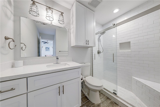 bathroom featuring toilet, vanity, hardwood / wood-style floors, and a shower with shower door