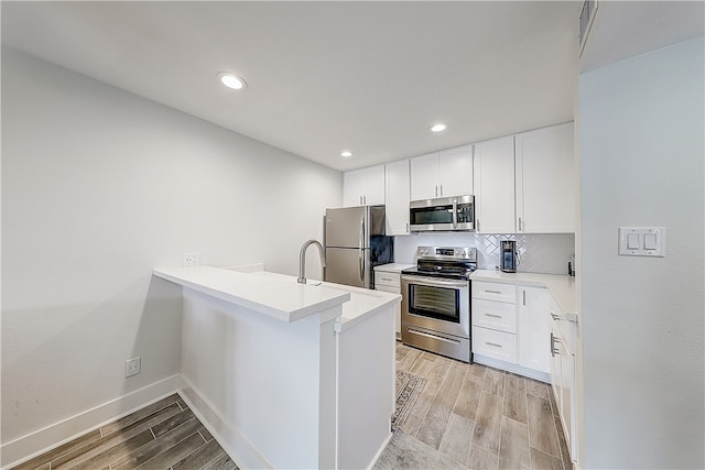 kitchen with white cabinetry, appliances with stainless steel finishes, backsplash, and light hardwood / wood-style flooring