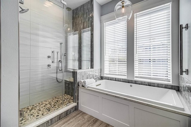 bathroom with a shower stall, a bath, and wood finished floors