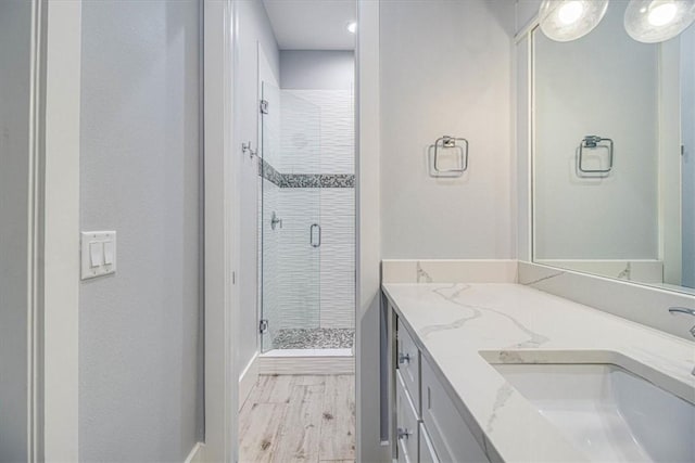 bathroom with wood finished floors, a shower stall, and vanity