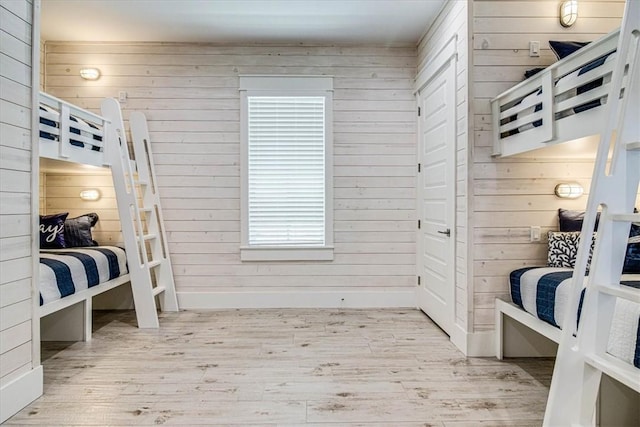 bedroom featuring wooden walls, baseboards, and wood finished floors